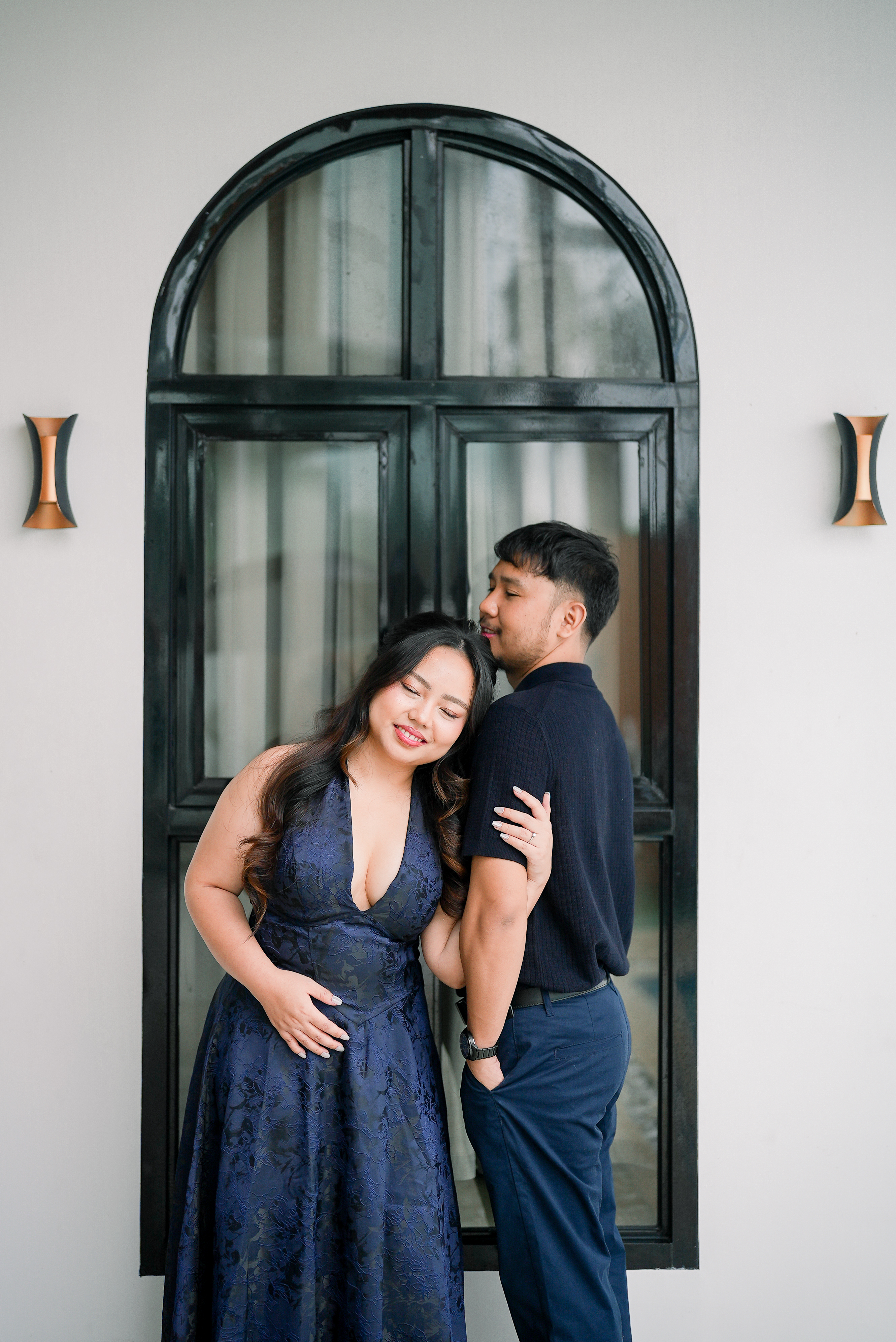 Rosette leaning against Benj in front of an arched window