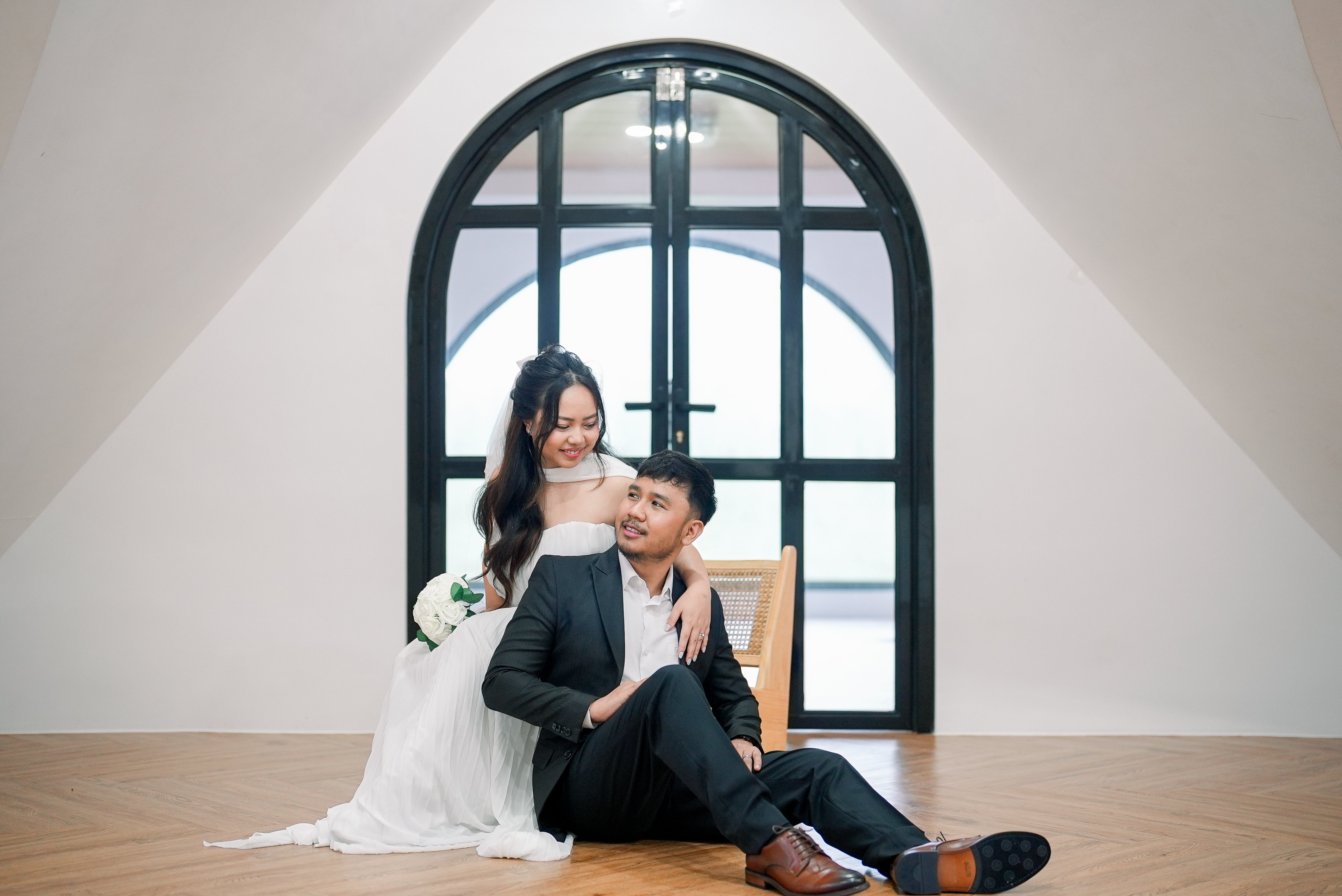 Rosette standing beside Benj seated in front of an arched window